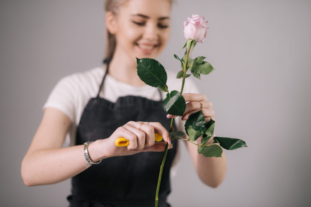 A woman cutting leaves from a rose stems