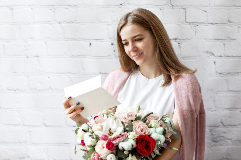 A Woman Smiling while reading a letter with a flower bouquet