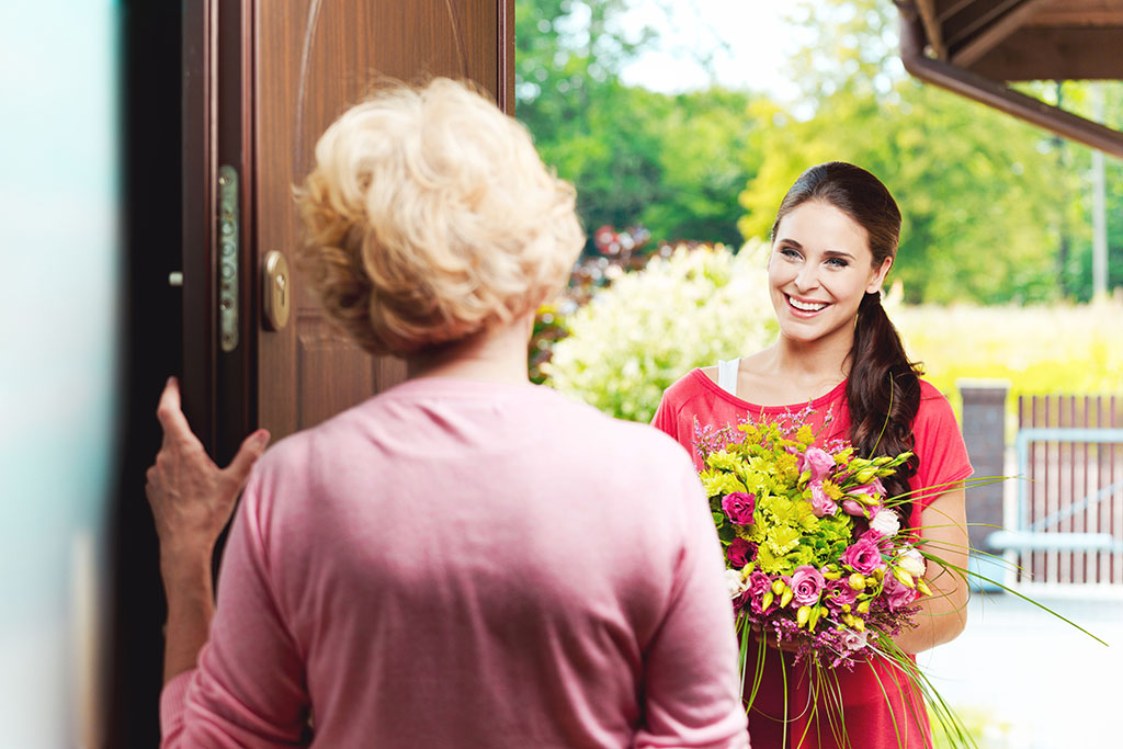 A Woman Gifting Flower Bouquet to an old Woman