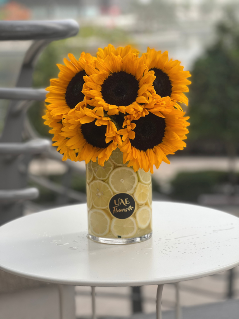 Bright yellow sunflowers in a vase covered with orange peels to give it an exotic look is one of the best flowers for men