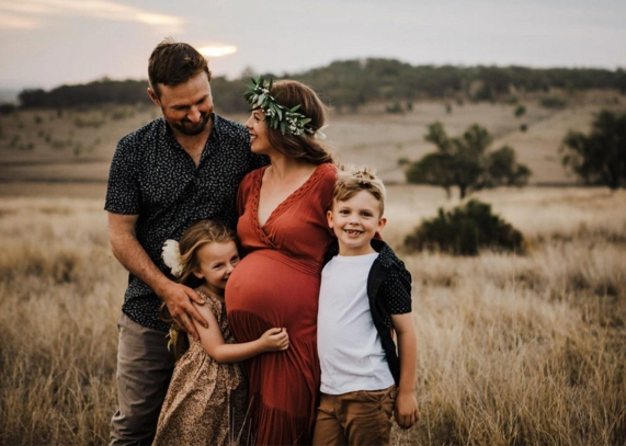 A family posing for a maternity photo in a field, capturing the joy and anticipation of the holiday season.